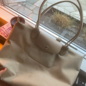 Longchamp väska beige  - Säljer min longchamp väska som är köpt inne på tradera. ❤️skicket är helt okej, men rätt så sliten… Nypris ligger på runt 1300kr men jag säljer den för 400 (PRISET KAN DISKUTERAS)😘