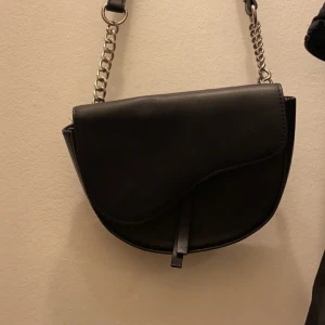 Svart axelremsväska  - Svart Axelremsväska från Kappahl, använd väldigt få gåmger och är i väldigt bra skick. För plats för mobil och mer där inne. Går att justera längden på bandet💗  För fler bilder eller info skriv privat💗