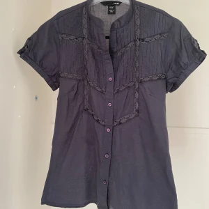 Mörkgrå blus från H&M - Säljer en snygg mörkgrå blus från H&M i stl 34. Perfekt för både vardag och fest. Den är aldrig använd och bara tvättad innan fotograferingen. Köpare står för frakt.