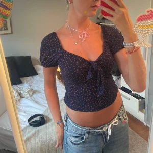 Söt prickig topp med knytdetalj framtill  - Söt topp från märket petites. Mörkblå med lätt orangea prickar i bra skick