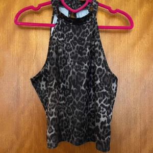 Leopardmönstrad ärmlös topp från Romwe - Säljer en leopardmönstrad topp från Romwe i storlek L. Toppen är ärmlös och har en tight passform. Den är tillverkad i ett stretchigt material. Toppen har en hög hals med knappar i nacken och en liten öppning på ryggen. Katt finns i hemmet, men allt jag säljer är nytvättat och rollat ✨