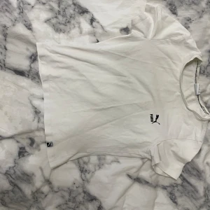 Vit t-shirt från Puma - Säljer en vit t-shirt från Puma i storlek S. Den är gjord av bomull och har en normal passform. T-shirten har korta ärmar och Puma-loggan tryckt på framsidan. Perfekt för vardagsbruk eller träning. Skicket är bra, men den är lite skrynklig på bilderna!🤍