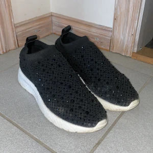 Svarta sneakers med glittriga detaljer - Säljer ett par jättesköna svarta sneakers med glittriga detaljer. Några stenar har lossat men det syns knappt i verkligheten. 