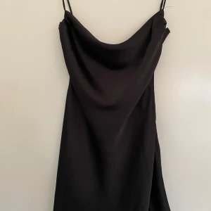 Svart satin klänning - Säljer en snygg svart klänning i satin. Perfekt för fest eller en utekväll. Aldrig använd, lapp finns kvar