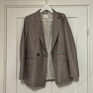 Kavaj - Oanvänd kavaj. Hundtandsmönster, i röd, beige och svart.