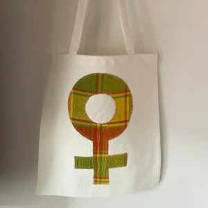 Tygkasse, tygväska, tygpåse  - Handsydd tygkasse med motivet ”feminist”.   Tillverkad i 100% återvunna textilier.   Mått: 32x35 cm  Hämtas på Södermalm alternativt skickas med post. 
