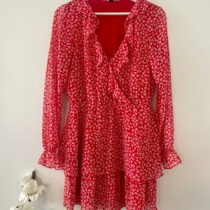 Blommig miniklänning - Röd miniklänning med vita blommor. Söta volanger på ärmar och kjoldelen❤️🍓