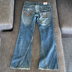 Lågmidjade utsvängda True Religion jeans! - Jättesnygga vintage lågmidjade true religion jeans! Storlek: W30 (passar 36). Innerbenslängd: 82cm, Midjemått 80cm. En knapp saknas på en av bakfickorna. Skriv för fler bilder! (Kan ej visa hur de ser ut på då de är för små för mig)💗 