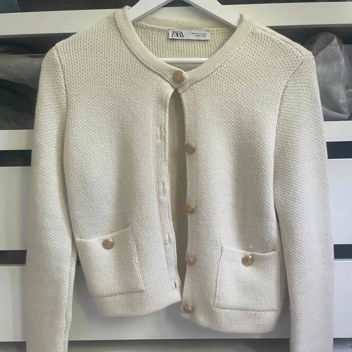 Vit kofta med guldknappar