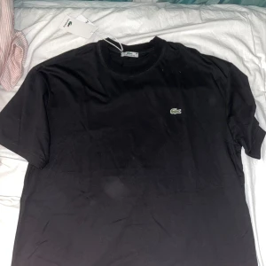 Lacoste t-shirt - En helt ny Lacoste t-shirt med tags på, fick den som present men den var för stor på mig, hör av dig kring funderingar 