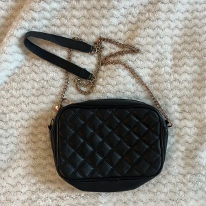 Svart väska - Svart crossbody bag med kedja. Väldigt väl använd! Kedjan är lite missfärgad och lite andra "fel" på baksidan. 