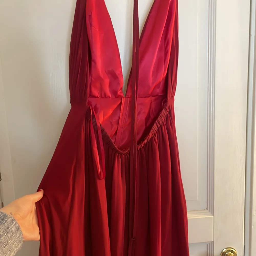 En röd balklänning med slits och öppen rygg med snören baktill som man kan välja själv hur som ska se ut i ryggen😍  Använd en gång, är av väldigt bra kvalite🙌 ORDINARIE PRIS 2100kr. Klänningar.
