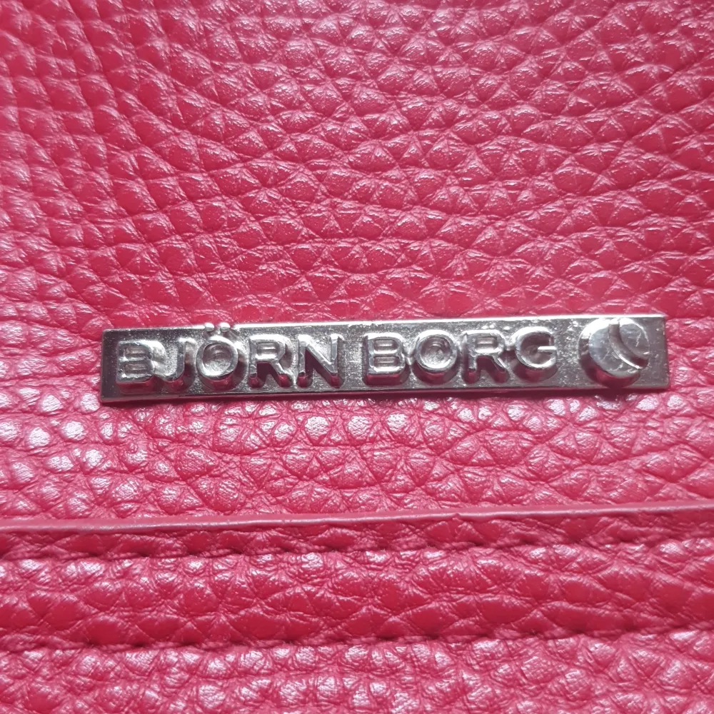 Röd Björn Borg väska med något slitna handtag, men med en axelrem som är ny. . Väskor.