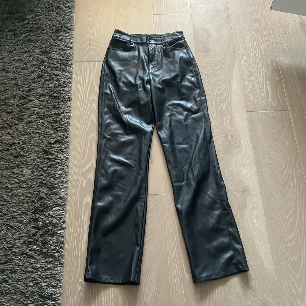 Svarta byxor från BikBok i storlek 38. Byxorna har en hög midja och är tillverkade i ett material som liknar skinn. De har raka ben och bakfickor.. Jeans & Byxor.