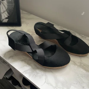 Skor kilklack  - Supersköna skor med kilklack. 7 cm höga i storlek 41.  Resårband som korsar över foten.