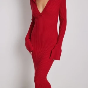 Ribbstickad klänning med trumpetarmar - Klänningen är från NA-KD och är aldrig använd. Den har ett stretchigt, ribbstickat material och en v-ringning med klassisk krage. Storlek: S Ursprungligt pris: 799kr