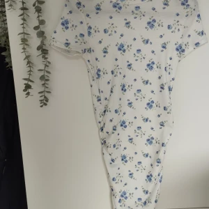 Tight Blommig Klänning - En tight blommig vit rynkad klänning för flickor! Sitter fint, har skönt ribbat material. Tyvärr klipptes etiketten bort men klänningen är till flickor med ungefära storleken 152. Plagget var använt bara 1-2 gånger. Mycket bra skick. 