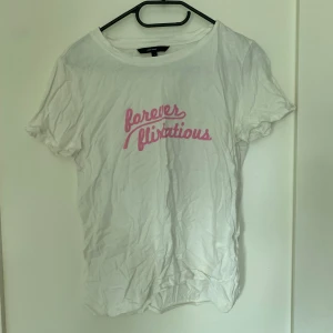 T-shirt  - Vit T-shirt med tryck på bröstet, knappt använd.