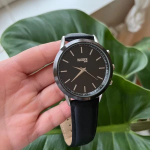 Steve Madden SMMW012 klocka - Säljer en snygg Steve Madden klocka med svart band i läderimitation. Klockan är i bra skick. Den har en silverfärgad ram och en svart urtavla. Klockan är perfekt för vardagligt bruk och passar både till casual och mer formella tillfällen. Klockan är 