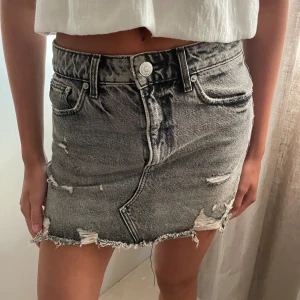 Grå jeanskjol - Urtvättad grå kort jeans kjol med ”slitdetaljer” 