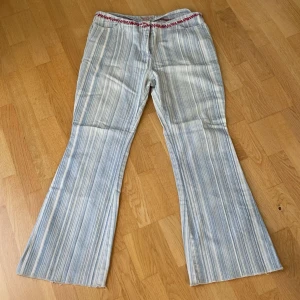 Randiga jeans - Vintage randiga jeans som är flared och snygga! Midjan skulle jag säga är 32-33 och längden 32!  De har fina röda detaljer och är i bra skick! Skriv om ni har frågor!