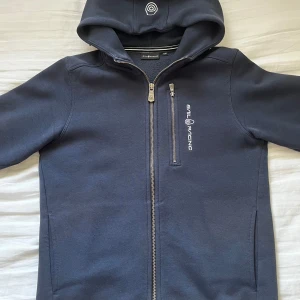Sail Racing kofta - Detta är en Sail Racing kofta i marinblå som nästan aldrig har använts. Storleken på den är 160.