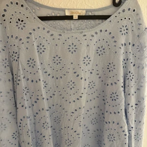 Blus  - En ljusblå blus från rose bud med ett vackert broderat mönster. Blusen har långa ärmar och en rund halsringning. Storlek 44 men passar mig med 34/36 utmärkt!