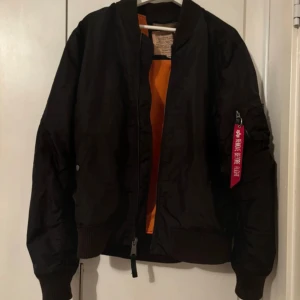 Alpha jacka  - En svart jättefin alpha jacka med orange på insidan, någon liten lös tråd som är lite lös som man ser på sista bilden men annars inget. Storlek L i fint skick. 