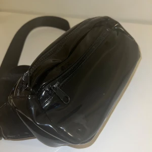 Midjeväska| Svart  - Svart midjeväska med en lite ytterficka och en stor ficka. Perfekt för att hålla mobilen på ett säkert ställe samtidigt med dig.