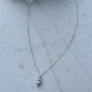 Halsband - Ett silvrigt halsband med en vit/lila snäcka! Size: M, 40cm (Ej justerbar, kedjan är i mässing) 🤍💜