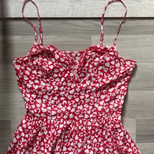 Klänning - Jättefin röd blommig klänning med vit mönster🤍 knappar och volanger på överdelen 🎀 Perfekt klänning till sommaren!