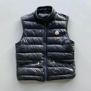 Moncler Gui - Moncler Gui väst i helt ok skick. Självklart äkta. Skulle säga 5/10. Hål på ryggen (skriv för bild), hål vid fickan ifram, dragkedjan är bytt, sytt på en bit under fickan då den (syns inte). Necktag är borta. Skriv för fler bilder eller vid frågor🤝😁