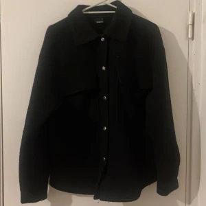 Svart vår kappa - Svart vår kappa som är medellång, precis över rumpan. Storlek S från Gina tricot. Har använts i ungefär 1 vår. Är i väldigt bra skick.