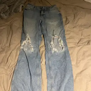 Högmidjade jeans med hål från bikbok. De är lite vida längst ner och är långa i passformen. Använda men i bra skick