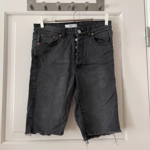 Shorts - Långa grå shorts från Ellos i storlek 38. Knäpps med knappar. Stretchigt material. Går till ovanför knäna på mig. Använda men i bra skick. Bara att fråga om det är något du undrar! Kan mötas på Järntorget i Göteborg eller skicka, köparen står för fra