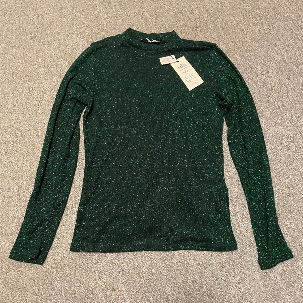 Grön, glittrig tröja med halvpolo från only. Helt ny med lappen kvar. Köpt på only. (nypris är 150kr). Toppar.