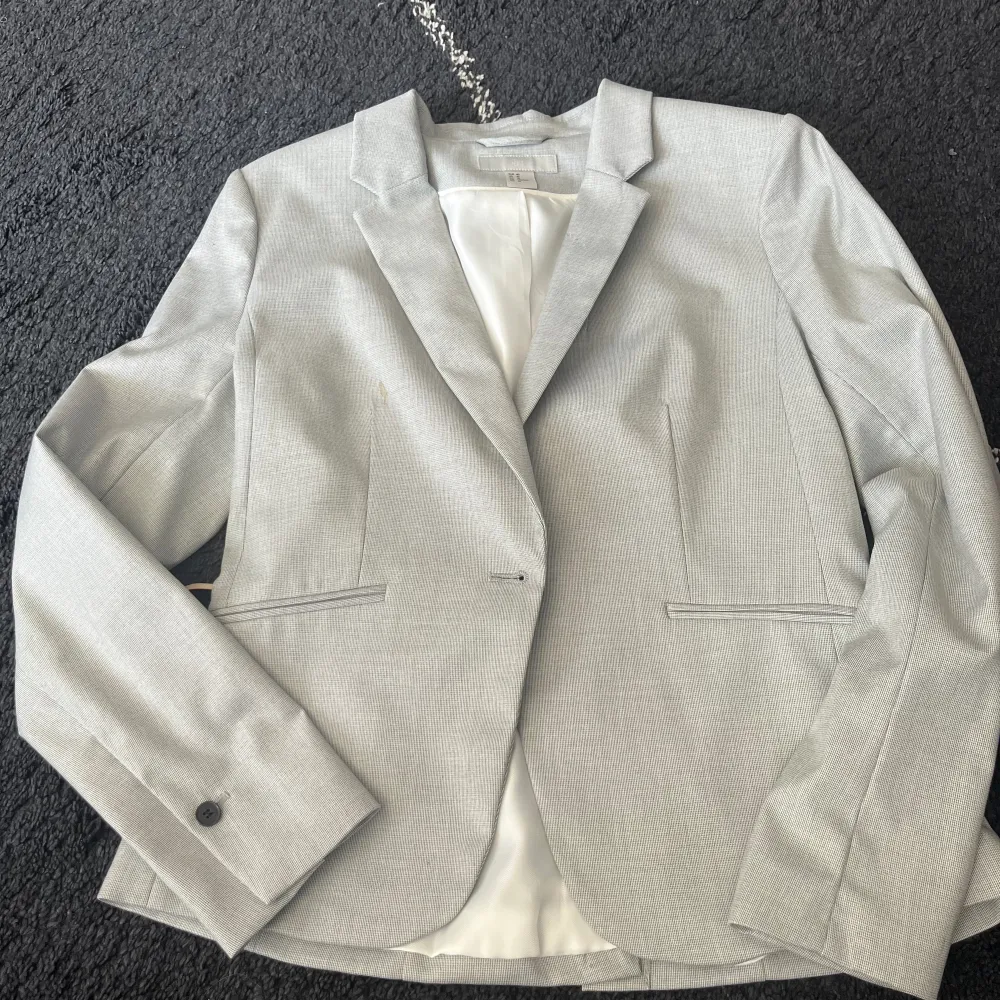 En jätte fin ljusgrå kostymjacka från H&M i strl 40. Använd endast en gång men har en liten kaffe fläck. Den är dock inte så synlig.. Kostymer.