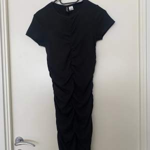 En svart tight klänning från H&M i storlek S. Rynkad både på fram och baksidan. Använd en gång.