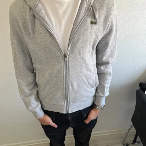 Grå Lacoste tröja - Grå Lacoste kofta , 8/10 skick använd ett fåtal gånger , Priset kan sänkas vid snabb affär ( skriv i dm för fler frågor om varan )
