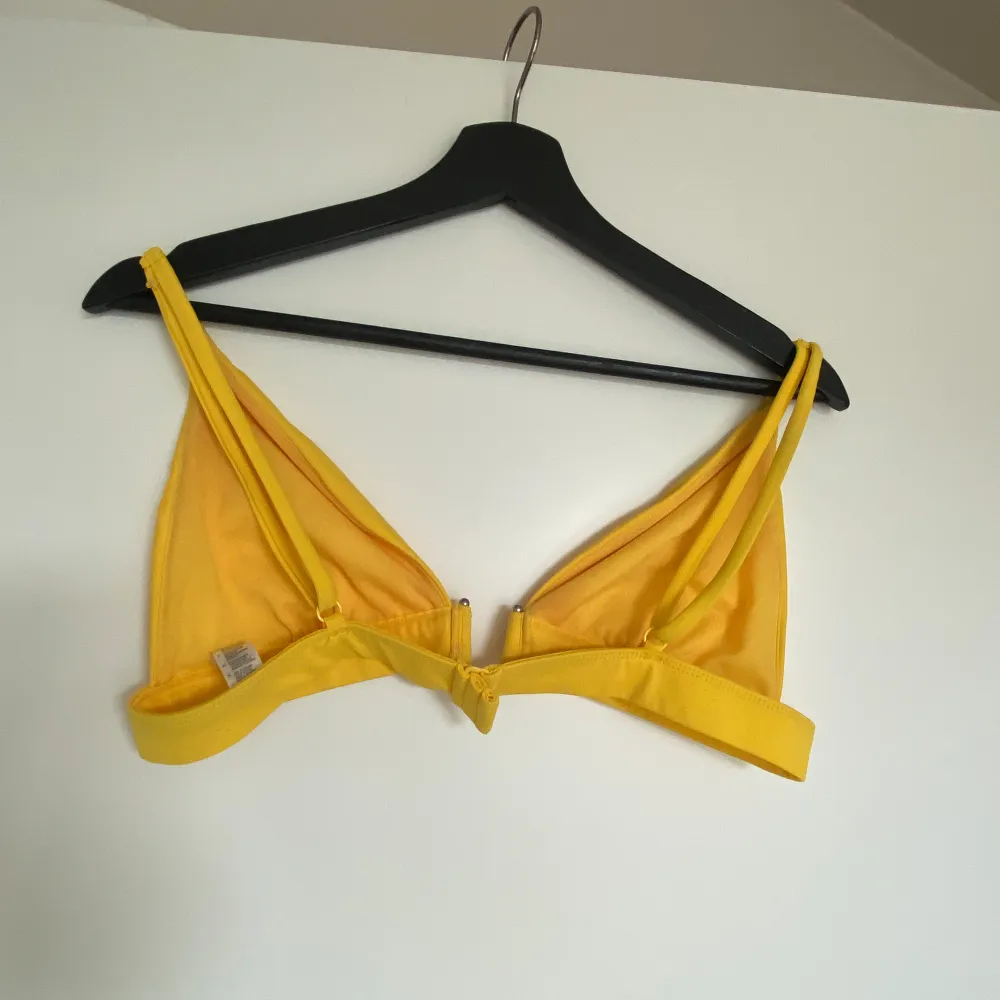 Säljer en söt gul bikinitopp från NA-KD. Bikinin är helt oanvänd och i fint skick. Bikin är liten i storleken.. Övrigt.