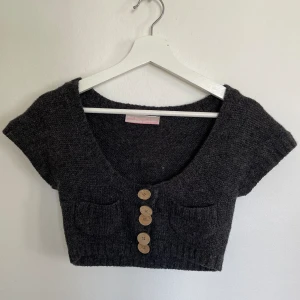 Bolero - Stickad mörkgrå bolero med en rosa detalj🩶🩷