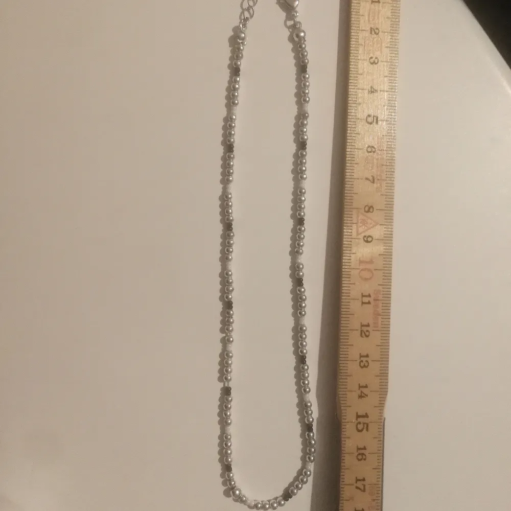 Halsband i silverfärg, inte äkta silver. Några svarta och vita pärlor med. Pärlorna är Små och halsbandet lite justerbart men stilen är att vara ganska litet runt halsen. . Accessoarer.