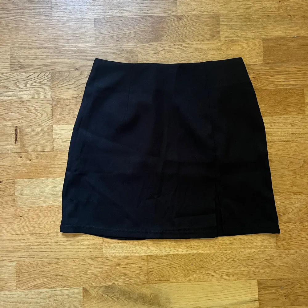 En svart kjol  med slits i fram, i storlek S (ej använd). Kjolar.