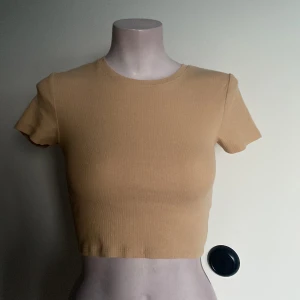 Beige crop top - Tajt beige crop top, i storleken S. Armarna sitter lite konstigt på plastfiguren, men gör inte det annars.