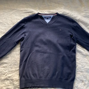 Tommy hilfiger - Tröja - En mörkblå tommy hilfiger v-neck tröja i st. 164 men passar garanterat XS och förmodligen S också. Modellen är 175cm lång. Fint skick utan några större skador. Nypris ca 500-600 kr