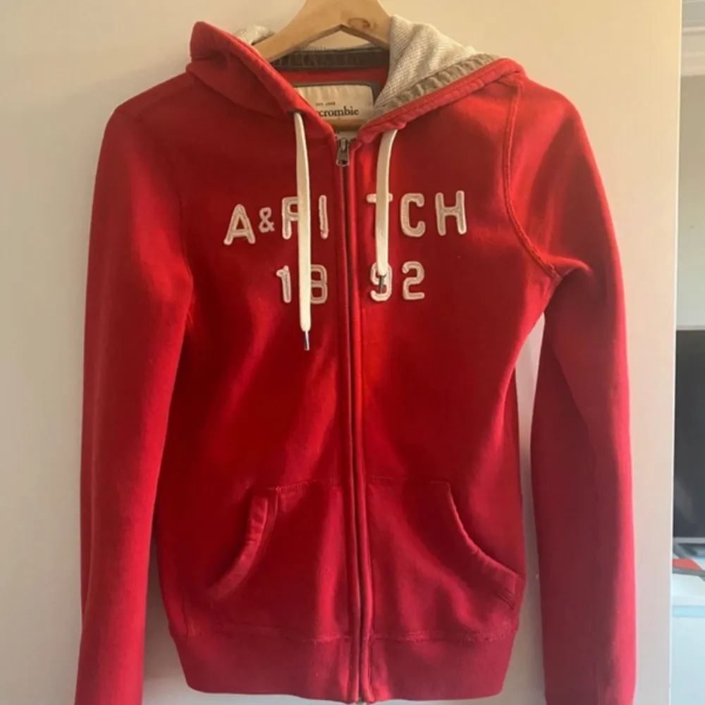 Superfin röd hoodie från Abercrombie & Fitch! Small Huva med grått foder  Fickor fram  Dragkedja  Snören  Allt toppenbra! . Hoodies.