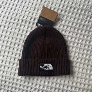 North Face mössa - Brun The North Face mössa, helt oanvänd (endast testad). Nyskick, etiketten sitter även kvar. Säljer för att jag upplevde den liten för mitt eget huvud.   One size! Inköpspris var 299kr. 