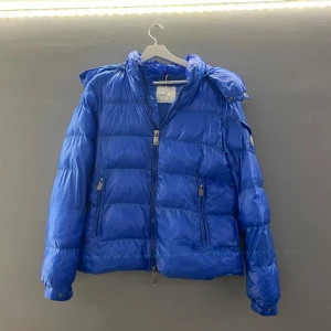 Moncler jacka - Säljer nu denna väll använda Moncler jackan. Den är väl använda och har lite defekter som vissa små missfärgningar och två små hål. Den har en luva som är avtag bar. Det är bara att höra av sig vid frågor eller om man vill ha flera bilder🤗🤗🤗