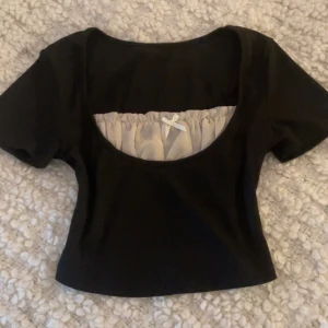 Svart cropped t- shirt - Jättefin cropped t-shirt med vit tunn byst och rosett som är perfekt för både basic och alt stil!  Har inga permanenta fläckar/ skador och har bara använts några gånger
