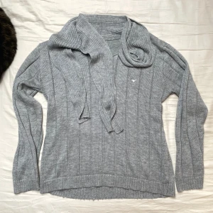 Armani stickad tröja - Mysig stickad tröja från Armani. ”Scarfen” runt halsen är en snygg detalj som gör att den kan styleas på lite olika sätt. Fint skick!  Skriv för fler bilder/mått etc. Pris kan diskuteras.